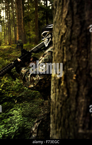 Maskierte Soldaten hinter einem Baum Stockfoto