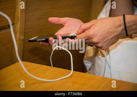 Mann schließen Sie Hände sein Handy an ein Ladegerät während auf seinem Bett liegend. Stockfoto