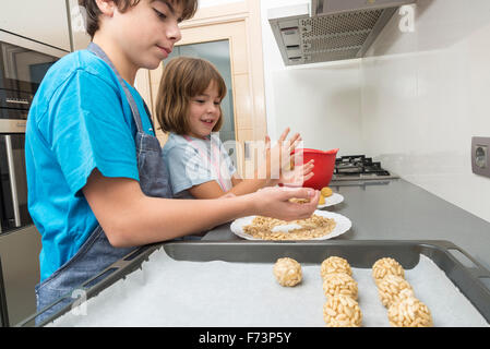 Kleine Mädchen und Jungen kneten Marzipan für bilden panellets in der Küche. Stockfoto