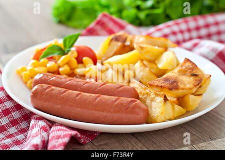 Bratwurst mit Bratkartoffeln und Gemüse auf einem Teller Stockfoto