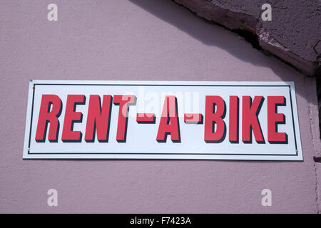 Mieten Sie ein Fahrrad-Zeichen auf Steinmauer Stockfoto