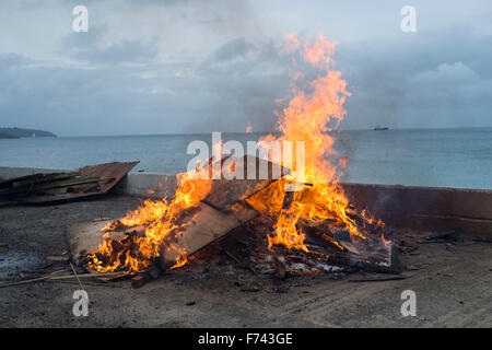 Ein Lagerfeuer an der Seite des Gylly Beach Cafe, Falmouth Cornwall wie sie Holz und andere Abfälle verbrennen Stockfoto