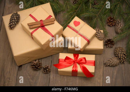 Weihnachten-Komposition mit Geschenken, Red Ribbon, Baum und Kiefer Tannenzapfen auf dunklem Holz im Vintage-Stil Stockfoto