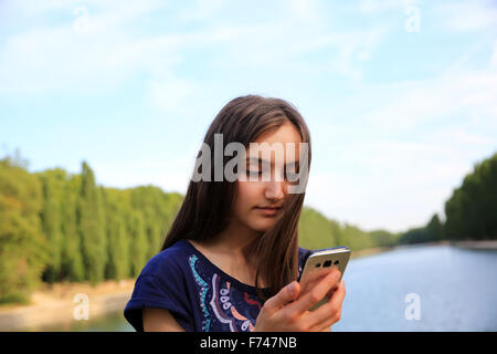 Mädchen mit einem Mobiltelefon liest die Nachricht im park Stockfoto