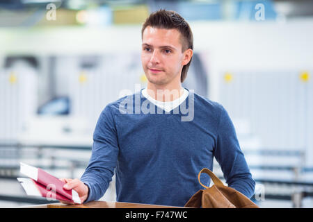 Junger Mann mit Pässen und Boarding Pässe an der Rezeption im Flughafen Stockfoto