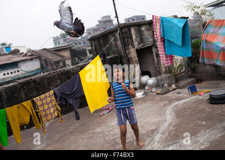 DHAKA, Bangladesch-17. November: ein Kind spielt mit einer Taube auf dem Dach eines alten Buildingin alten Dhaka am 17. November 2015. Alten Dhaka ist ein Begriff verwendet, um die historische Altstadt von der modernen Hauptstadt Dhaka beziehen. Es wurde im Jahre 1608 als Jahangir Nagar, der Hauptstadt von Mughal Bengal gegründet. Stockfoto