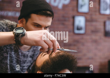Nahaufnahme des jungen dicht Friseur Pflege Bart gut aussehender Mann mit einer Schere im Barber shop Stockfoto