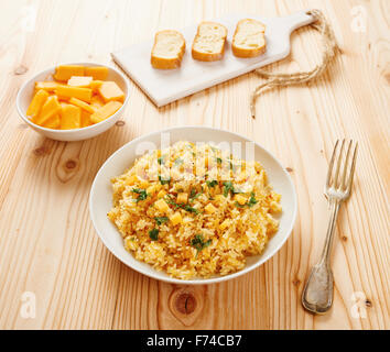 Kürbis-Risotto auf weißen Teller und Tisch aus Holz Stockfoto