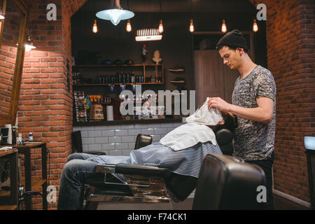 Barbier, finishing Pflege und kümmert sich um Kunden Gesicht im barbershop Stockfoto