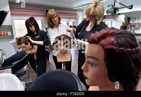 Bitterfeld, Deutschland. 9. November 2015. Kursleiter Pia Seelmann (c) überwacht Friseur Auszubildenden Karina Neddermeyer (r) und Jennifer Bechmann, wie sie ihren Friseur auf Puppenköpfe im Friseur-Studio des Figaro Bitterfeld GmbH in Bitterfeld, Deutschland, 9. November 2015 üben. Figaro Bitterfeld GmbH ist seit 50 Jahren Training professionelle Friseure. Foto: Hendrik Schmidt/Dpa/Alamy Live News Stockfoto