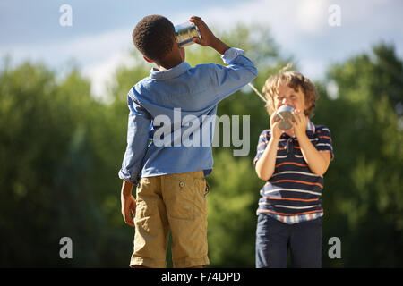 Zwei Jungen spielen Blechdose Telefon und Spaß im park Stockfoto