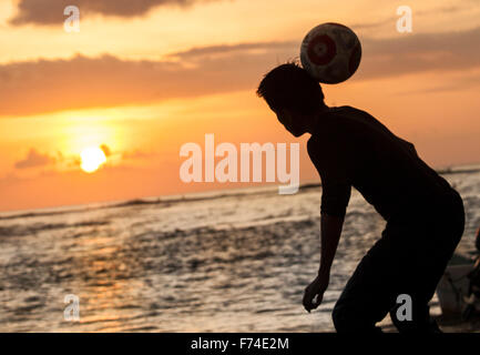 Fußball-Spieler leitet einen Ball am Strand bei Sonnenuntergang, Zihuatanejo, Guerrero, Mexiko. Stockfoto