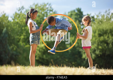 Junge springt durch Hula Hoop Reifen im park Stockfoto