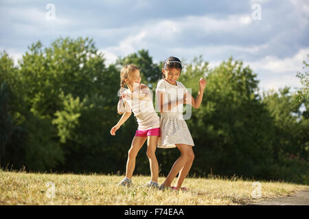 Zwei glückliche Mädels tanzen im Sommer und Spaß im park Stockfoto