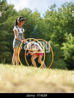 Zwei Mädchen mit Hula Hoops spielen im park Stockfoto