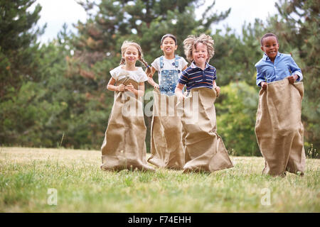 Kinder, die Spaß am Sackhüpfen im park Stockfoto