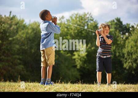 Zwei Jungen spielen Blechdose Telefon im park Stockfoto