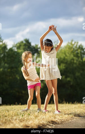 Zwei glückliche Mädels tanzen im Sommer im park Stockfoto