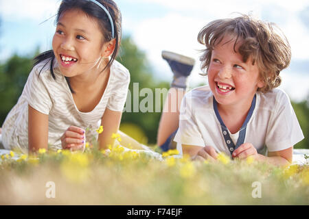 Mädchen und jungen Lachen und Blumen abholen Stockfoto