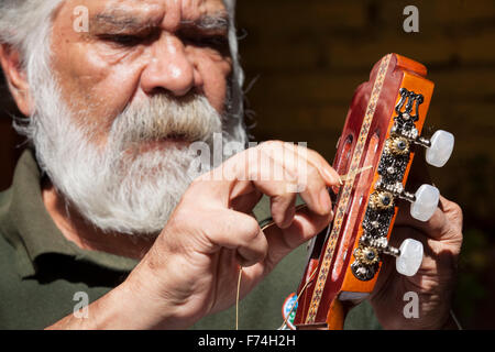 Gitarrenbauer Sistos Pasaye Saiten eines seiner Produkte vor einem Geschäft in Paracho, Michoacan, Mexiko. Stockfoto