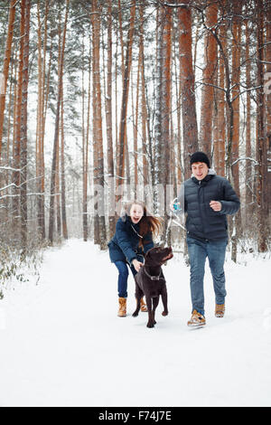 Junges Paar mit einem Hund Spaß im Winterwald auf Urlaub. Selektiven Fokus. Lebensstil der modernen Familienglück. Stockfoto