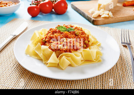 Tagliatelle mit Bolognese-Sauce auf weißen Teller und blauen Holztisch Stockfoto