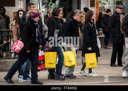 Shopper cross Oxford Circus, einige Rauschen und einige beladen mit Taschen, wie Oxford Street seine ermäßigte Angebote für schwarzen Freitag bereitet. Stockfoto