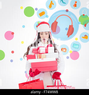 Zusammengesetztes Bild überrascht Brünette in Winterkleidung hält viele Geschenke und Einkaufstaschen Stockfoto