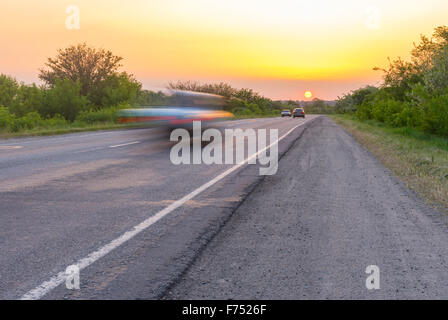 Sonnenuntergang über Landstraße mit schnellen Rennwagen zur Sonne Stockfoto