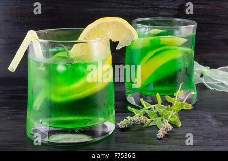 Hausgemachtes Mojito cocktail in einem gebogenem Glas und frischer Minze Pflanze auf dunklen Hintergrund Stockfoto