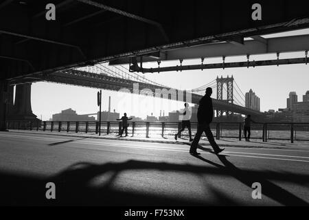 Zwei Chinatown Frauen ausüben, läuft ein Mann, eine andere geht beim betrachten die anderen entlang der East River Überführung bei Sonnenaufgang Stockfoto