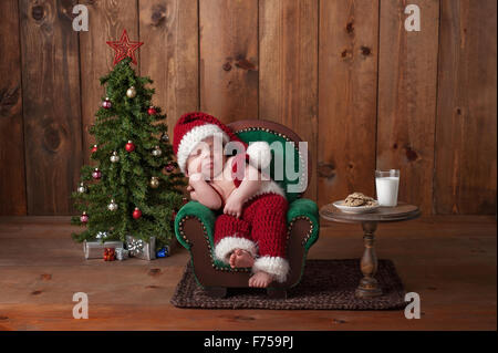 Neugeborenen, Baby junge Santa Anzug und schlafen auf einem kleinen Sessel. Stockfoto