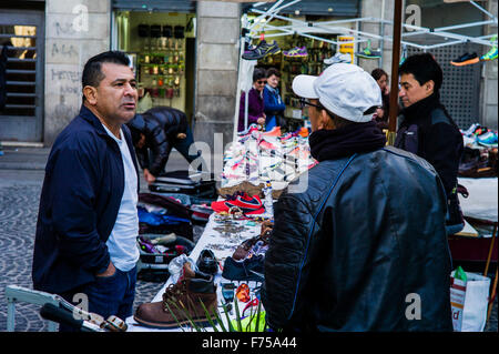 Zwei Personen zu sprechen, während bei einem Schuh Hersteller Stall in einem Straßenmarkt (Barcelona, Spanien) Stockfoto