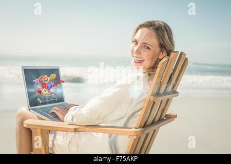 Zusammengesetztes Bild wunderschöne blonde auf Liegestuhl mit Laptop am Strand sitzen Stockfoto