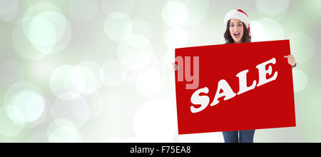 Zusammengesetztes Bild der hübsche Brünette in Santa Hut zeigt weiße Plakat Stockfoto