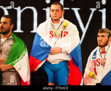 Houston, Texas, USA. 25. November 2015. Eine emotionale Artem Okulov (Mitte) von Russland hört seine Nationalhymne Afer Sieger der 85 Kilogramm-Klasse auf der Welt-Gewichtheben-Wettkämpfen in Houston, Texas. Brent Clark/Alamy Live-Nachrichten Stockfoto