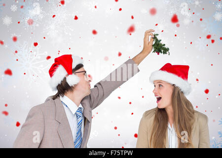 Zusammengesetztes Bild des Mannes trägt Weihnachtsmütze und hält Mistel mit überrascht Frau blickte ihn Stockfoto