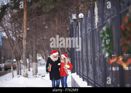 Glückliches Paar in Santa Hüte mit Weihnachtsgeschenken walking im freien Stockfoto