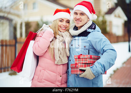 Junges Paar im Weihnachtsmann-Mützen hält Geschenke Stockfoto