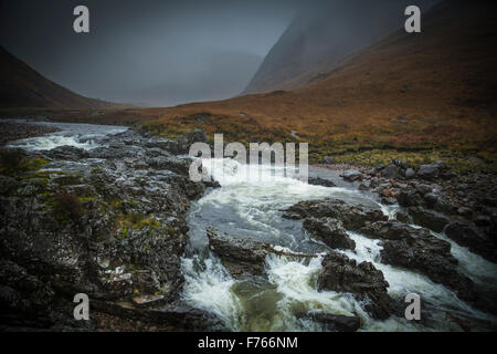 Niedrige Wolken, Nebel und Herbstfarben in Glen Etive mit dem Fluß Etive in voller Flut, Lochaber, Schottland Stockfoto