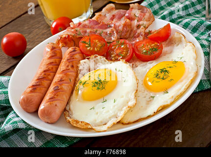 Englisches Frühstück - Toast, Ei, Speck und Gemüse im rustikalen Stil auf hölzernen Hintergrund Stockfoto