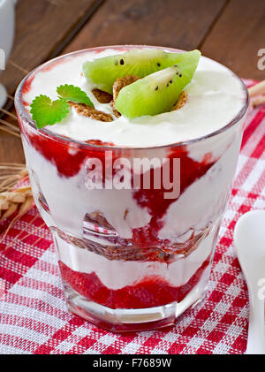 Gesundes Dessert mit Müsli und Obst in eine Glasschüssel auf den Tisch Stockfoto