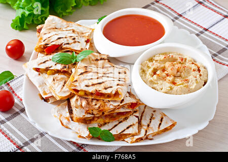 Mexikanisches Quesadilla mit Gemüse und Saucen auf dem Tisch in Scheiben geschnitten Stockfoto