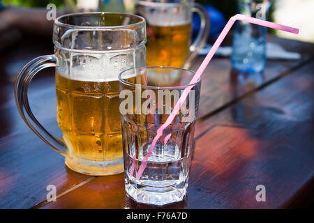 Einen Becher Bier und ein Glas Wasser stehen auf einem Tisch in einem café