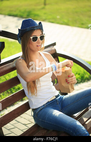 Mädchen aus einer Papiertüte auf der Straße trinken. raucht. Cowboy-Hut Stockfoto