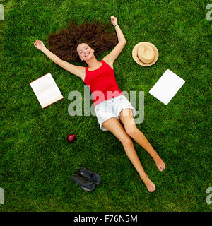 Schöne und glückliche junge Frau liegt auf dem Rasen Stockfoto