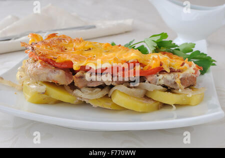 Gebackene Kartoffeln mit Zwiebeln, Fleisch und Tomaten mit Käse Stockfoto