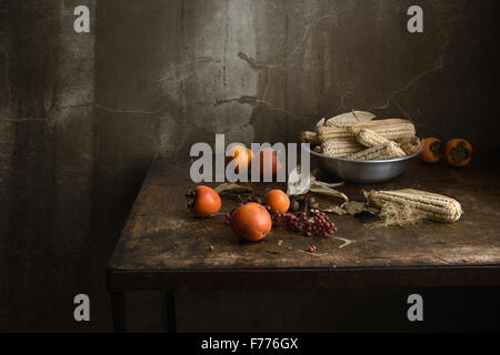 Stillleben mit Obst und Mais in einer Aluminiumschale auf einem alten Holztisch Stockfoto