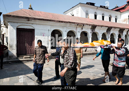 Menschen, die eine Leiche eines Mannes, der Feuerbestattung Ort für Beerdigung Pashupatinath Tempel in Kathmandu, Nepal Stockfoto