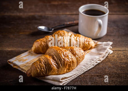 Frühstück mit frisch gebackenen Croissants und Kaffee auf hölzernen Hintergrund Stockfoto